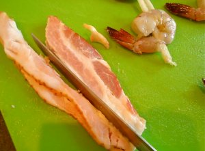 Prepare the bacon by cutting away the fatty part and just use the more meaty strips. You don't need much bacon per shrimp and less fat will means it will catch on fire less easily!